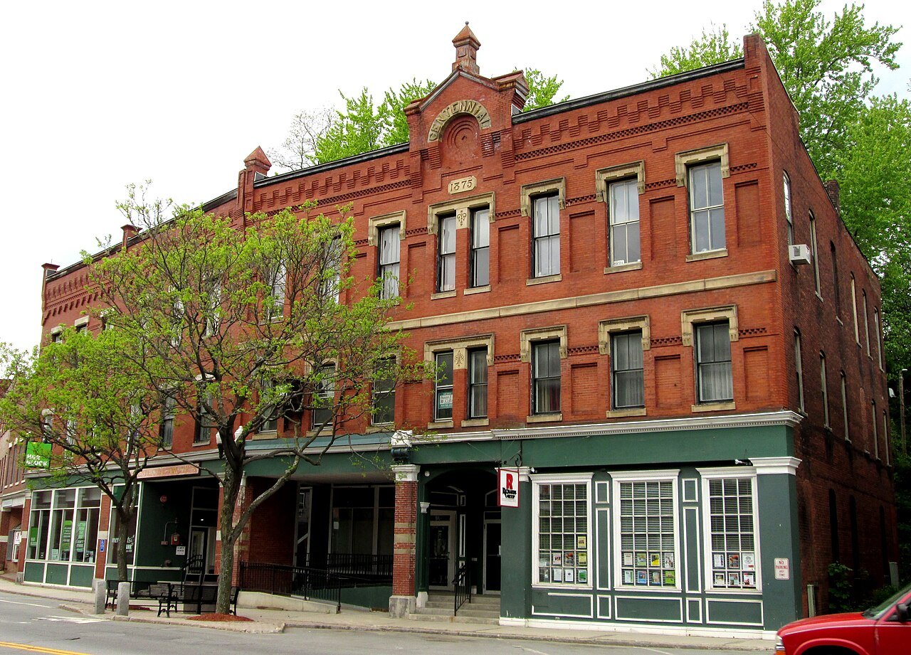 The Centennial Block, a red-brick Victorian building with green-trimmed storefronts.