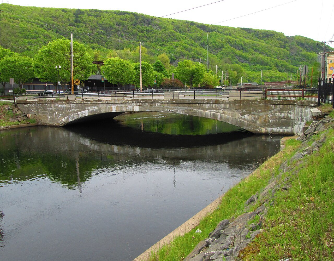 The Depot Street Bridge, a stone arch over the canal, with green hills above.
