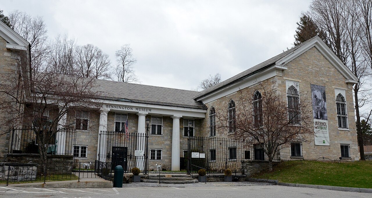 A stone building with columns in Old Bennington, behind a fence and bare trees.