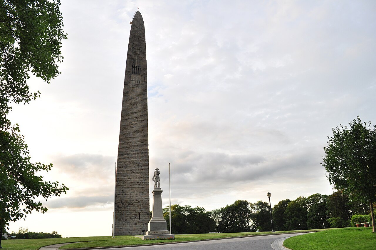 The Bennington Battle Monument, a pale obelisk rising from the grounds, with a statue at its foot.