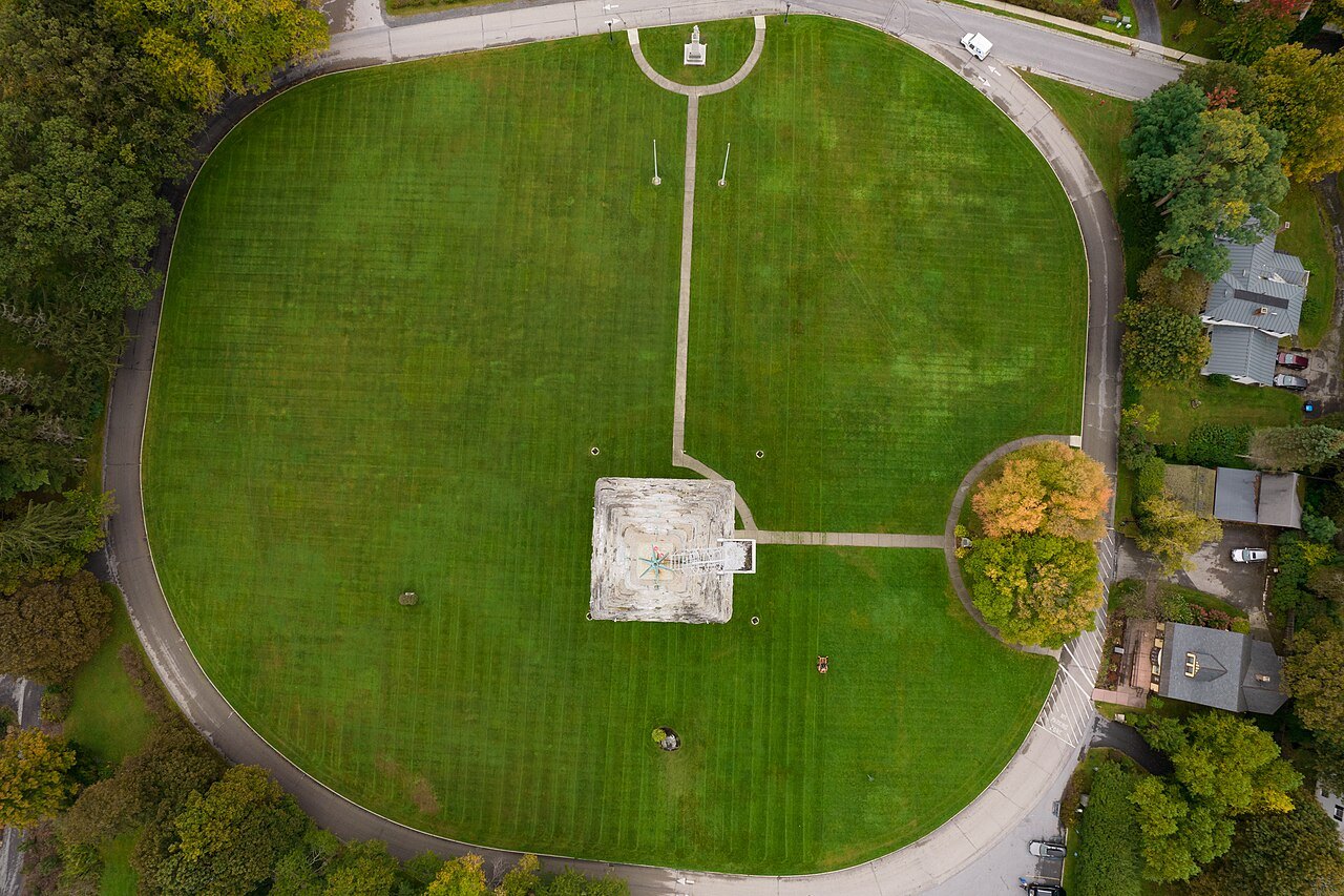 The monument's grounds from directly above, a green oval ringed by a path.