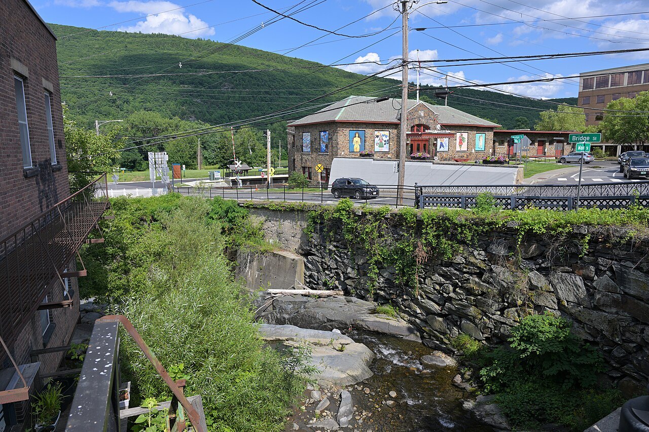 Whetstone Brook running below the Brattleboro Museum and Art Center, with a wooded hill behind.