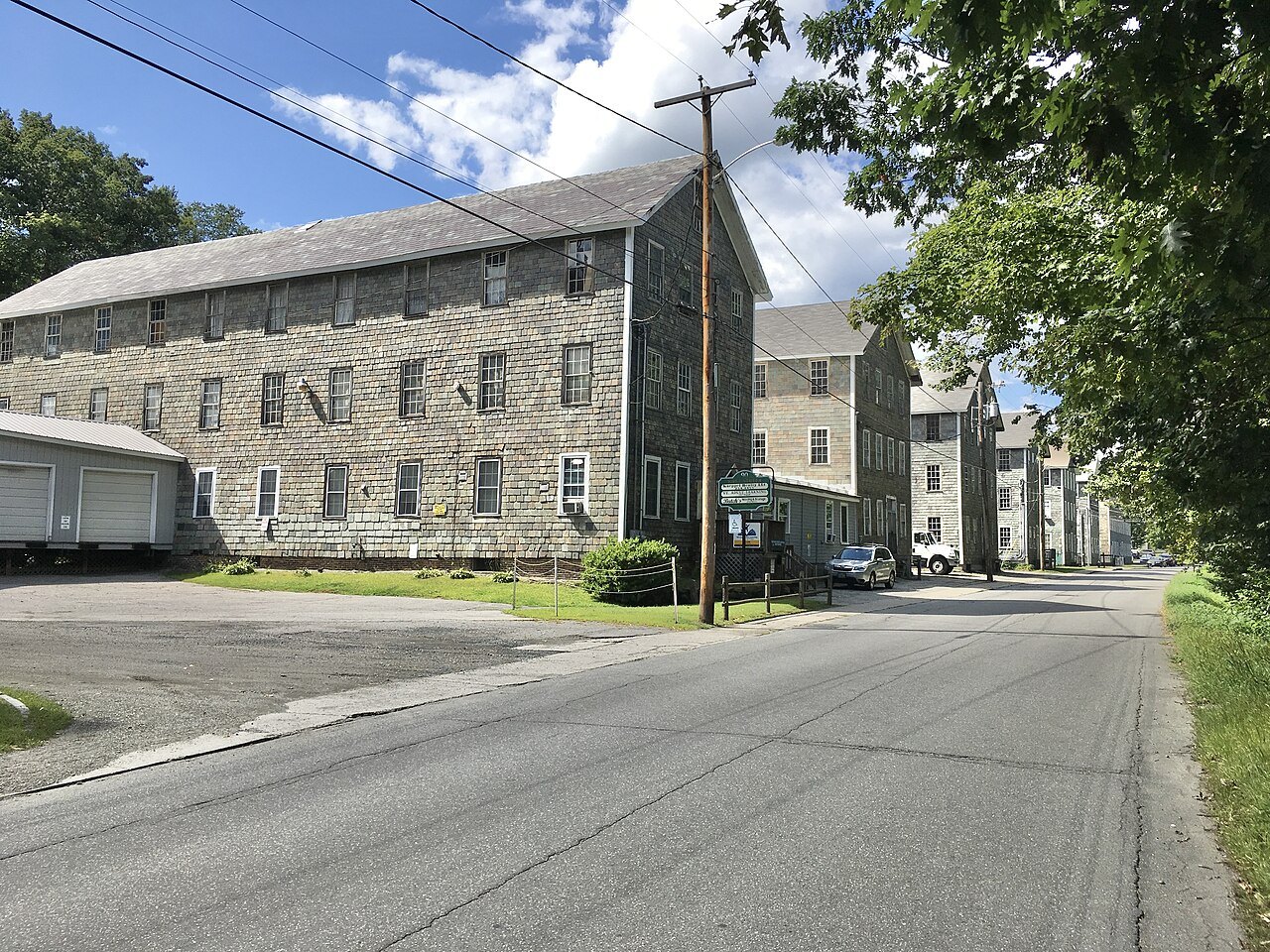 The long shingled mill buildings of the Estey Organ Company beside the road.