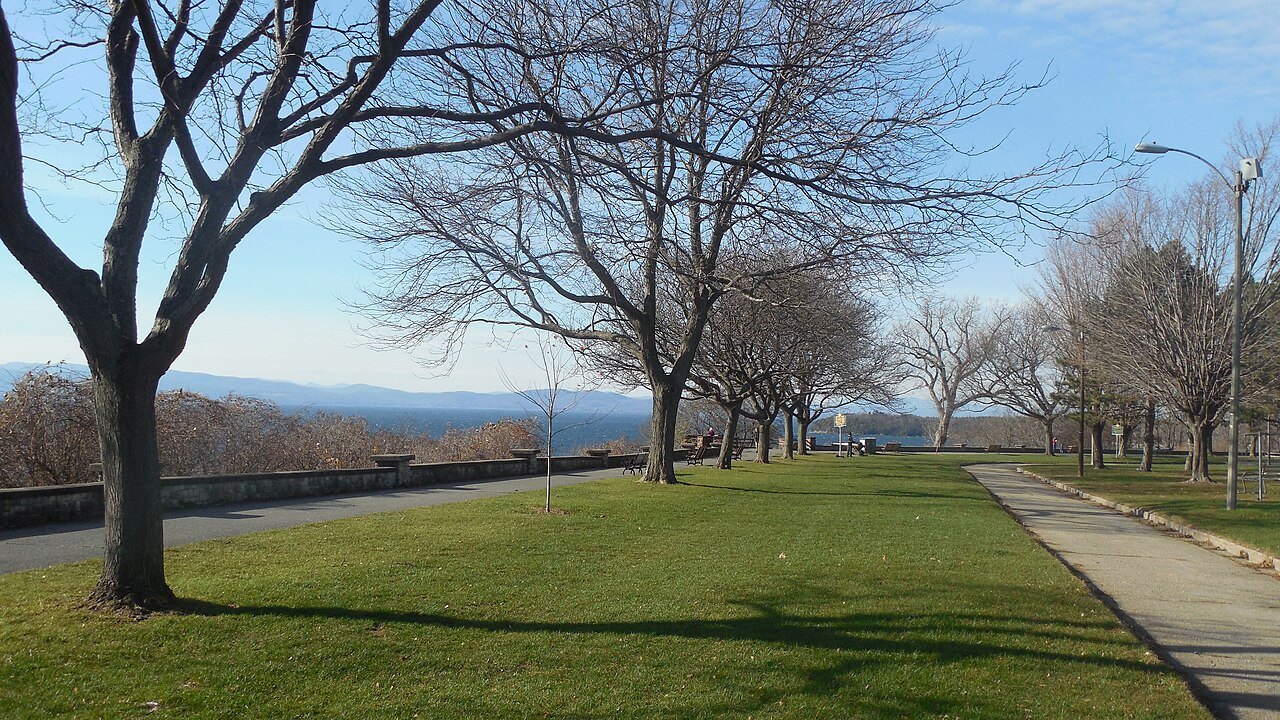 Battery Park in Burlington, a lawn and bare trees above the lake, with mountains across the water.