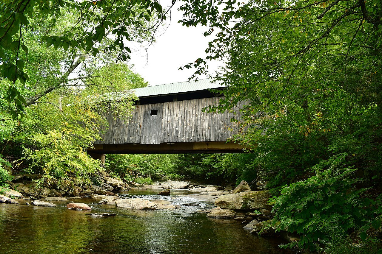 The Belvedere Mill bridge, a gray covered bridge above a woodland stream.