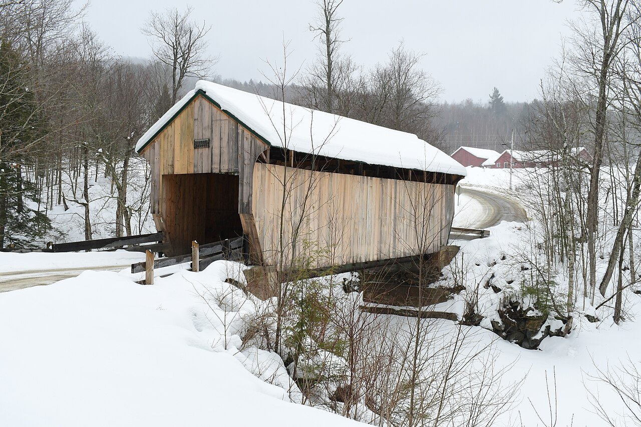 The Codding Hollow Bridge in snow, a weathered covered bridge beside a plowed road.