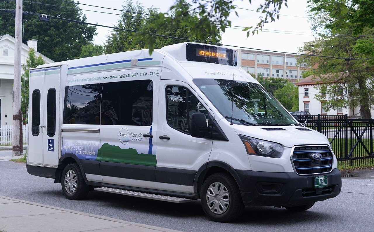 A white Green Mountain Community Network bus on a town street.