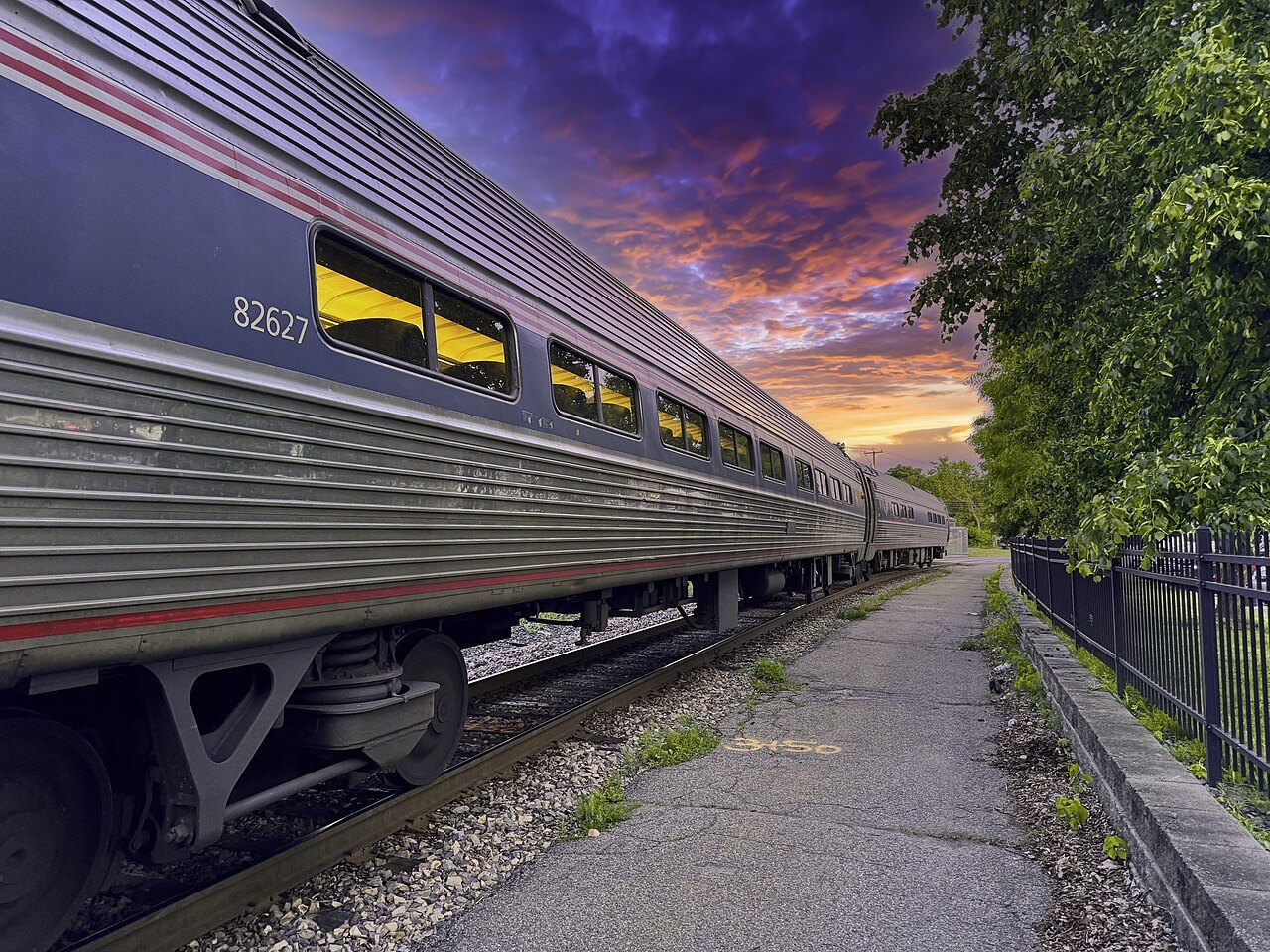 The silver cars of an Amtrak train in evening color at Essex Junction.