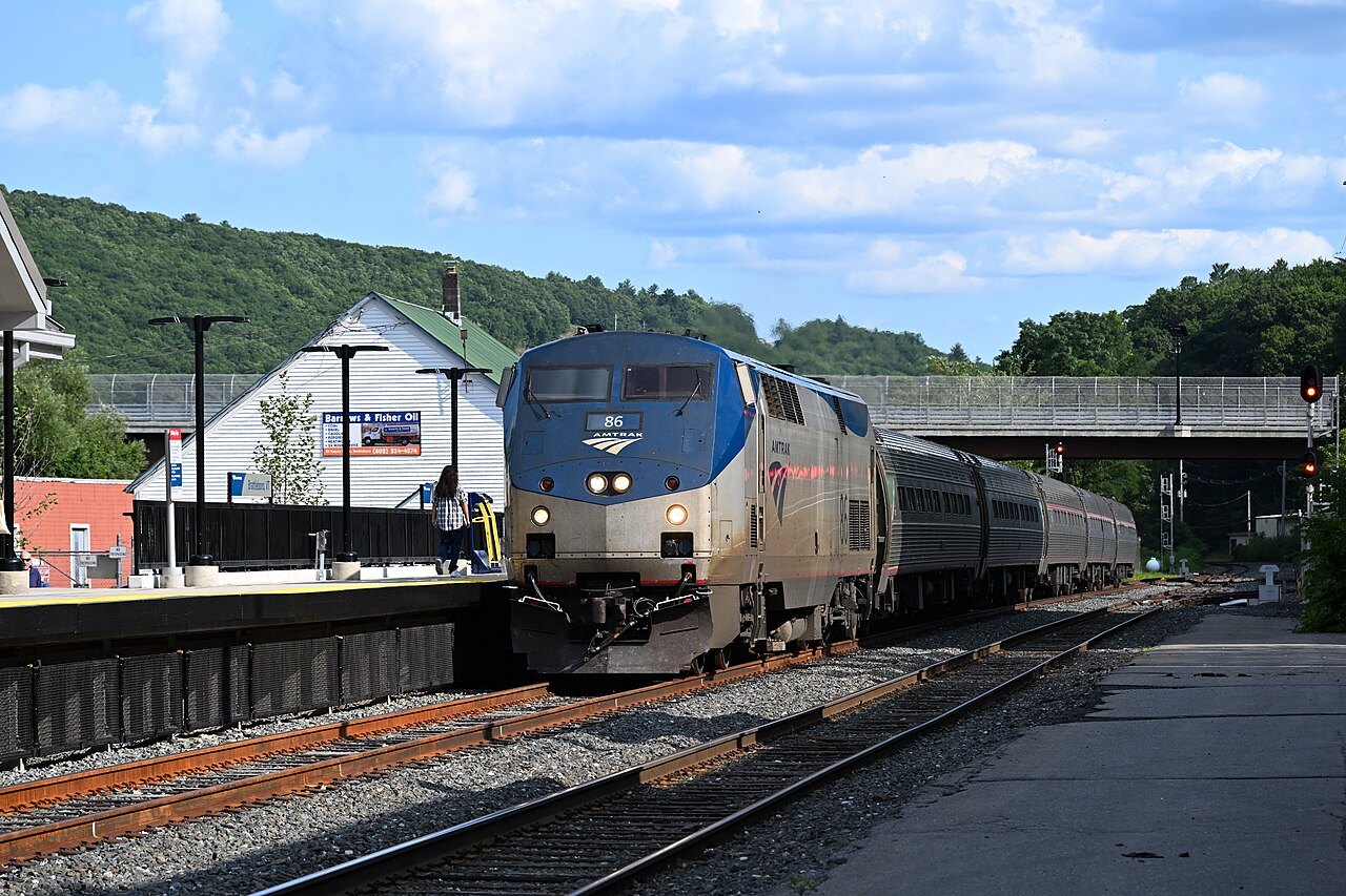 An Amtrak Vermonter arriving at the Brattleboro station past a crossing signal.