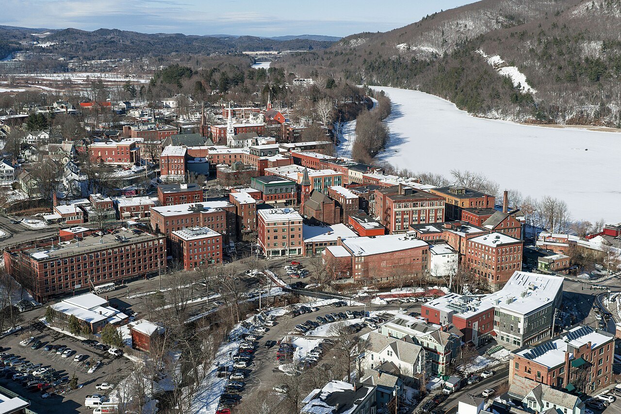 Brattleboro from above, brick mill buildings and a ski slope on the hill beyond.