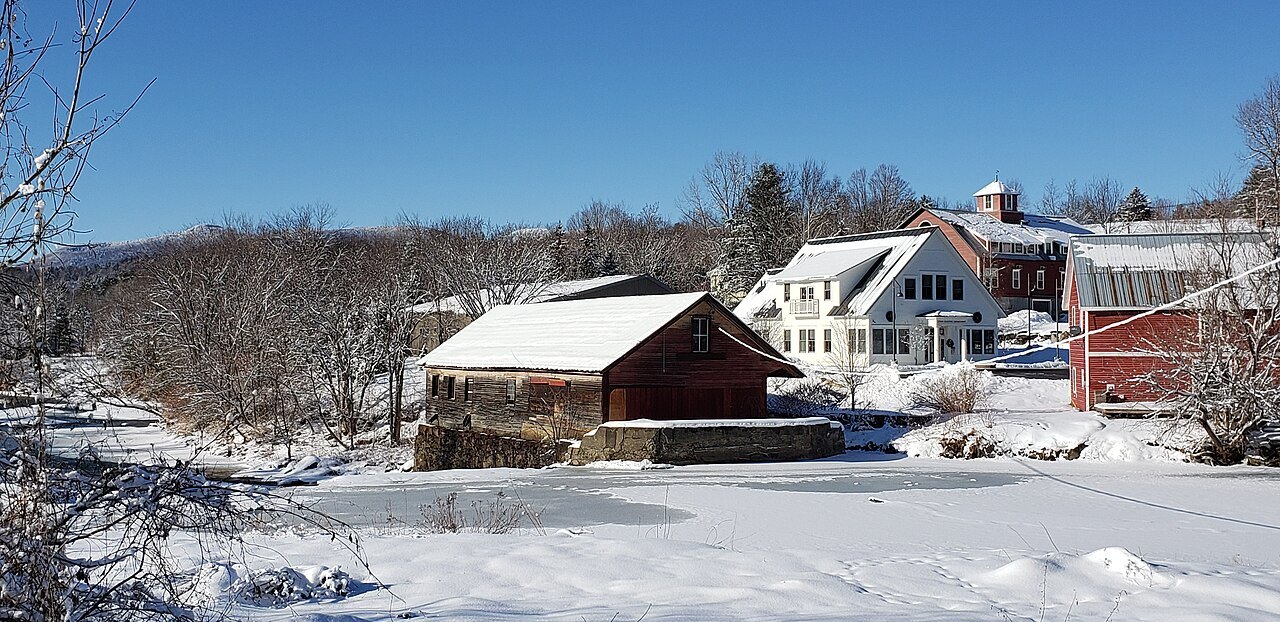 A sawmill and houses in snow, with a blue winter sky.