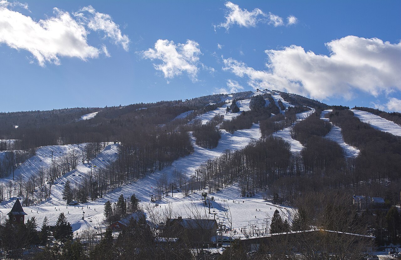 The ski trails of Mount Snow in winter, a snow-covered mountain under blue sky and cloud.