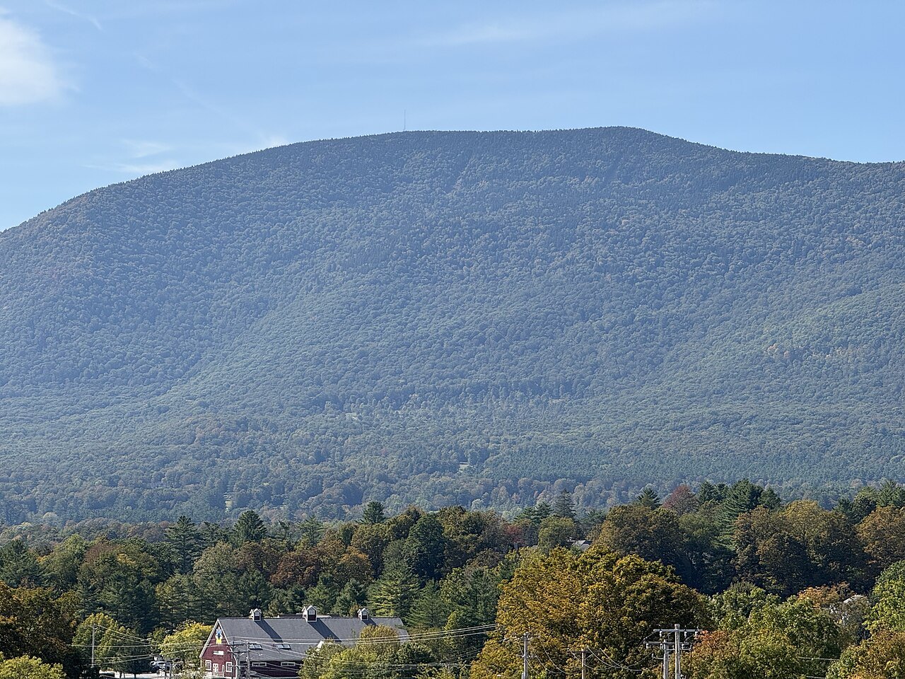 The long ridge of Equinox Mountain seen from the west above a village in the valley.