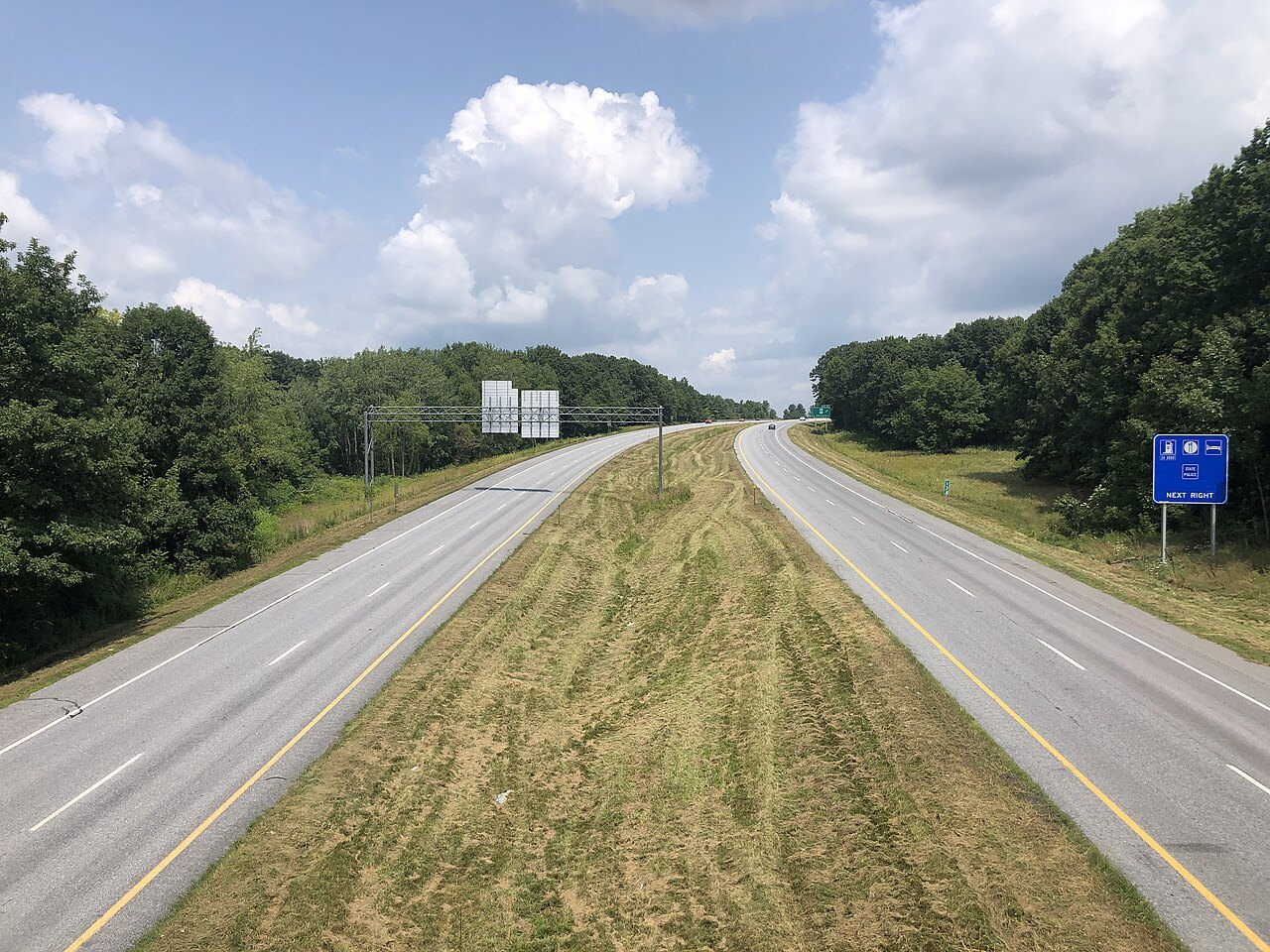 The divided highway north on U.S. Route 7, with a green exit sign ahead.