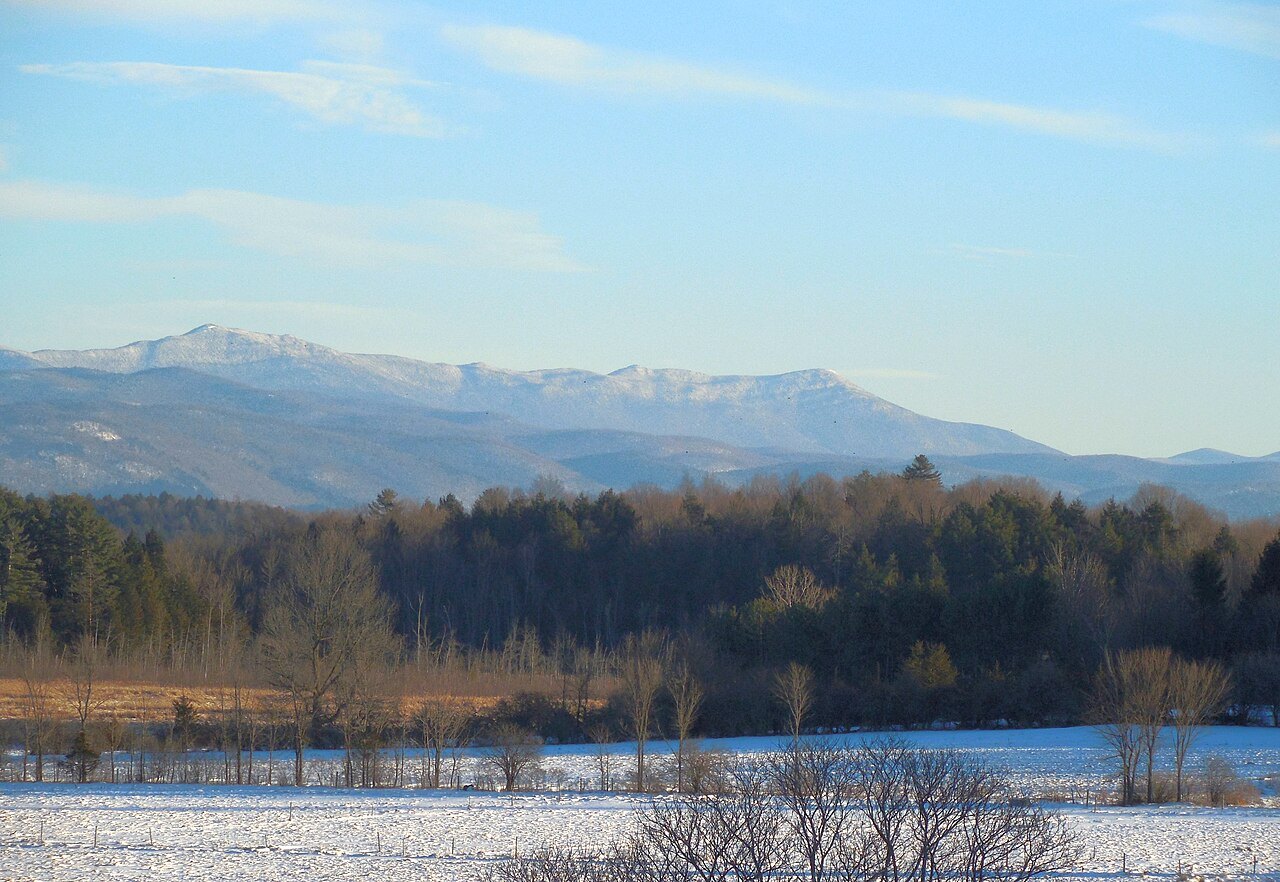 Mount Ellen and Mount Abraham from the west, snow on the peaks and bare trees below.