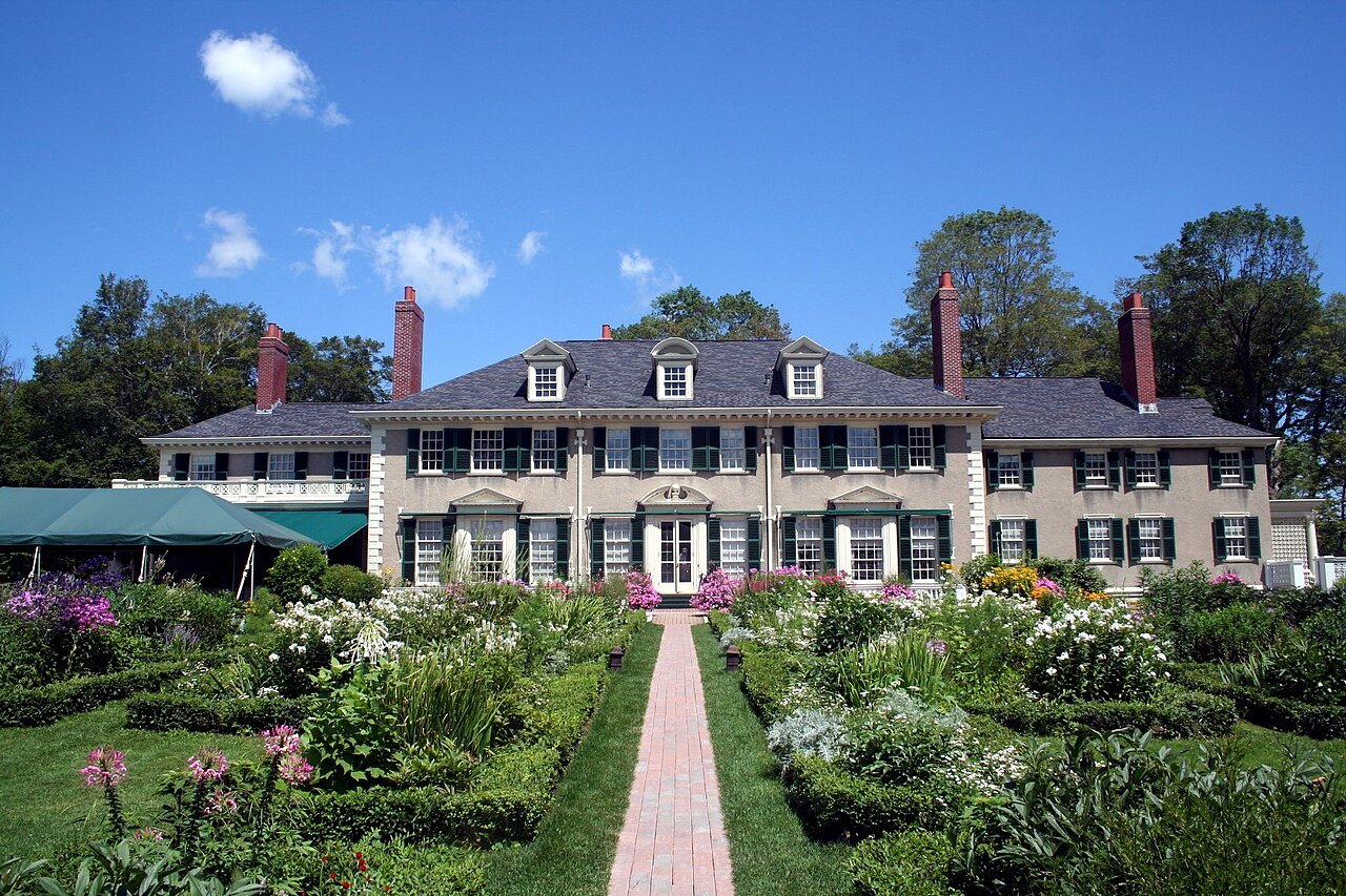 The garden's central brick path, flanked by hedged beds, leading to the house.