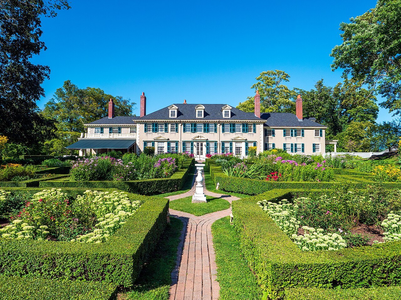 Hildene seen from the head of the formal garden, the house behind clipped hedges and borders.