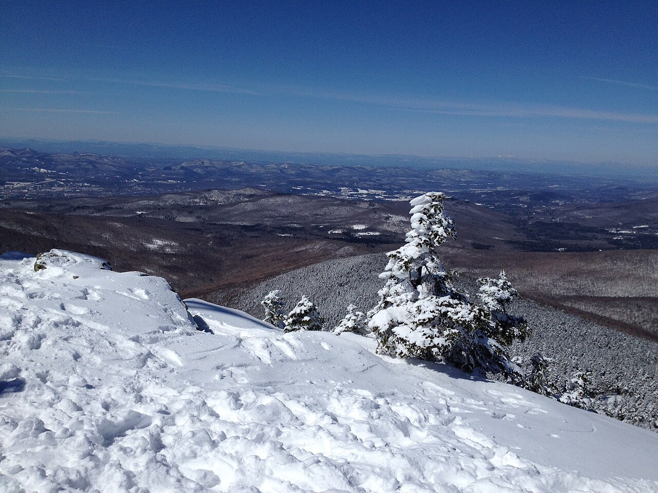 Snow and a rimed spruce on the summit of Killington, with the valley far below.