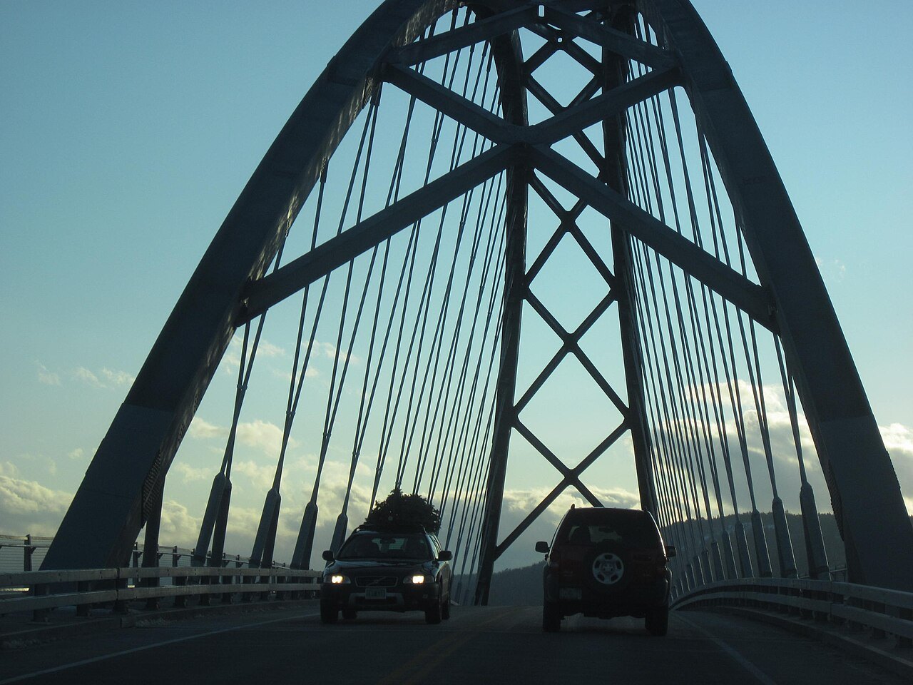 The arch of the Lake Champlain Bridge, seen from the road across it, with cars below.