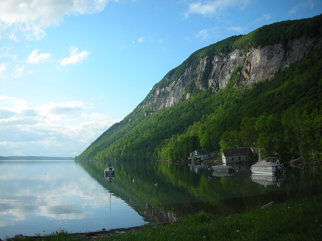 Mount Pisgah's cliff face and its reflection in still water at Lake Willoughby.