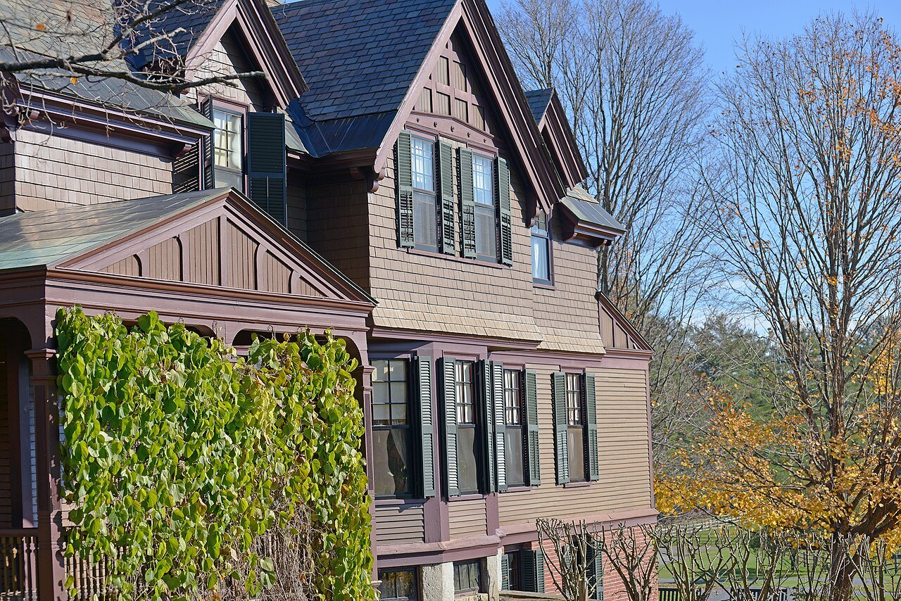 A shingled Queen Anne house with ivy on its wall, in the park at Woodstock.
