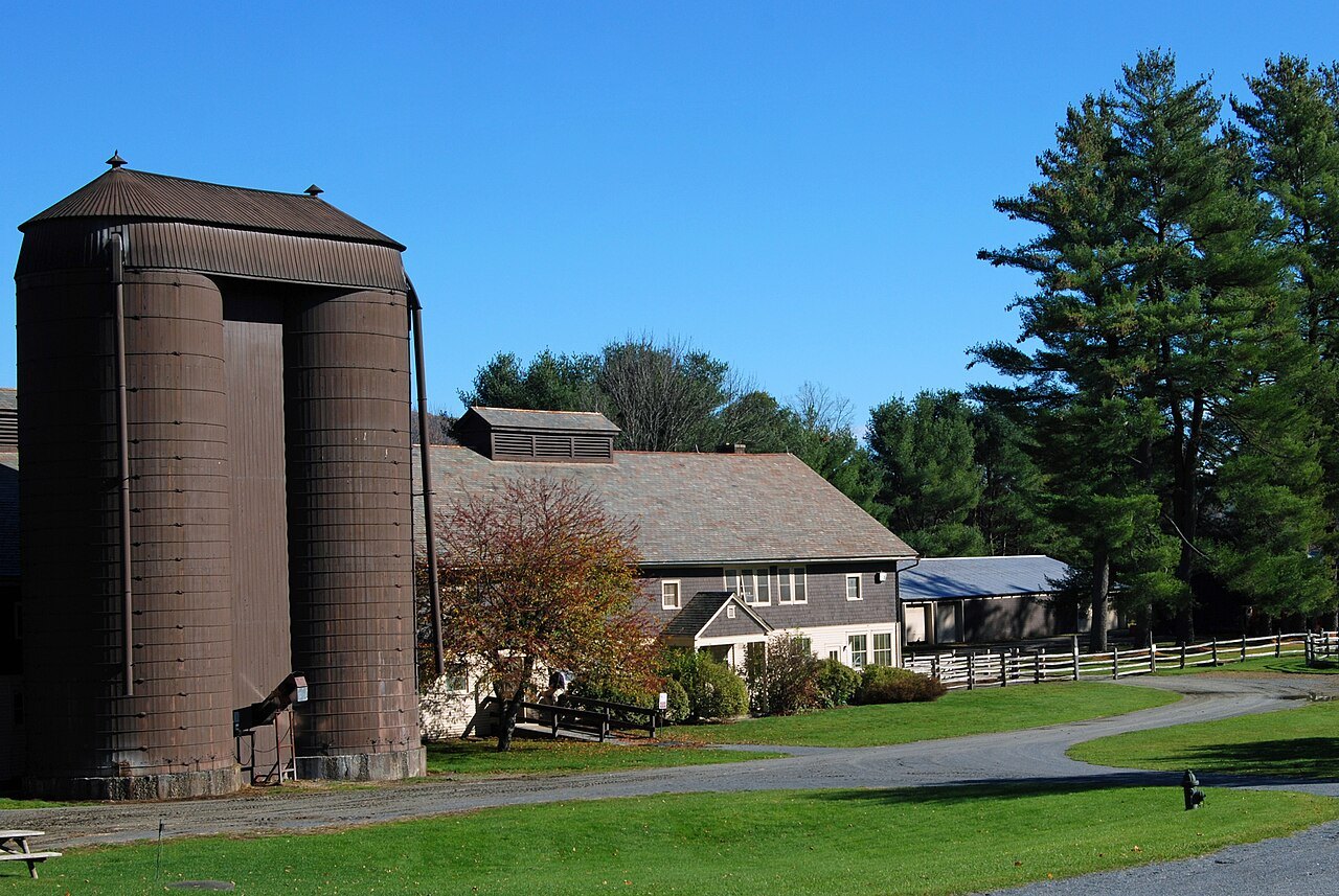 A tall brown silo beside long barns at the Billings Farm and Museum.