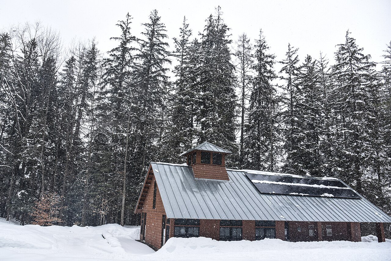 The Forest Center, a wooden building with a solar roof, in snow among spruce.