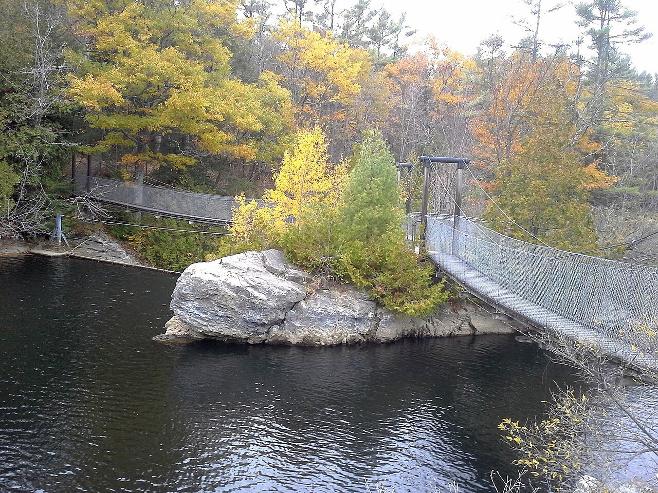 Belden Falls, a footbridge over a pool beside a rock island in autumn color.