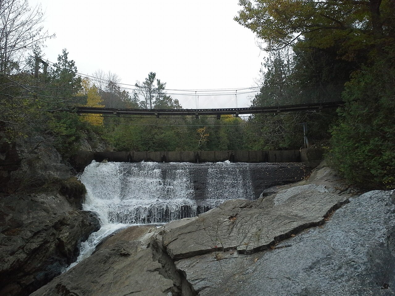 Belden Falls, water dropping over a ledge beneath a suspension footbridge.