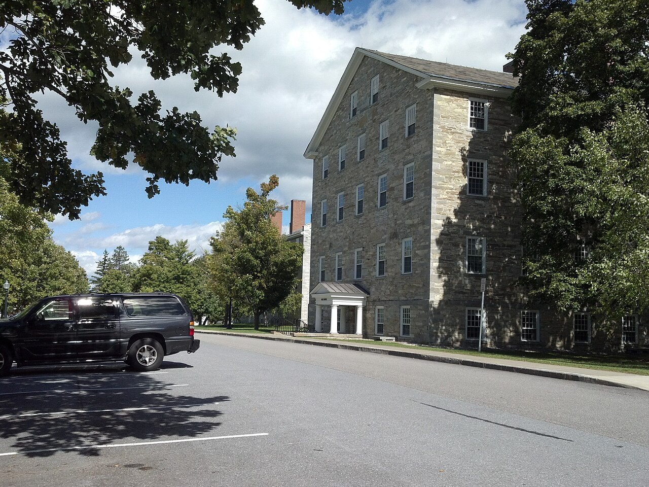 Stone Row at Middlebury College, a gray stone hall beside the road.