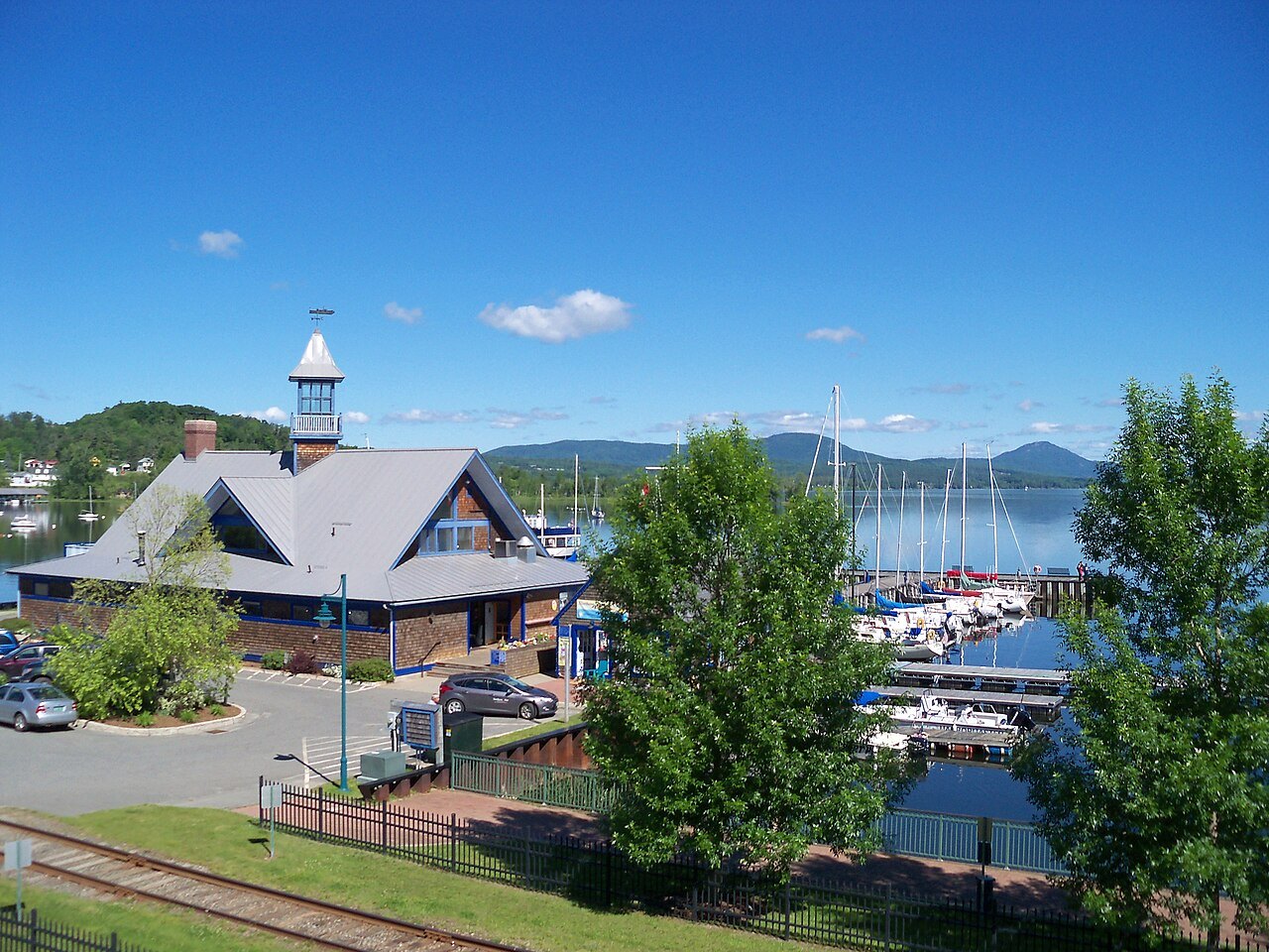 Newport's waterfront, a gabled harbor building and a marina below blue hills.