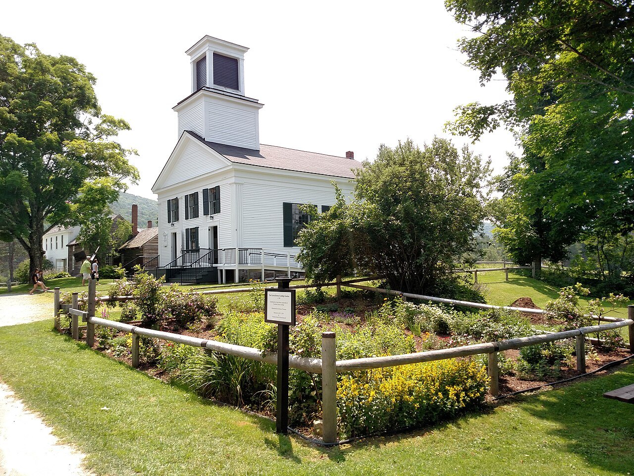 The Union Christian Church, white with a belfry, above a small garden with a sign.