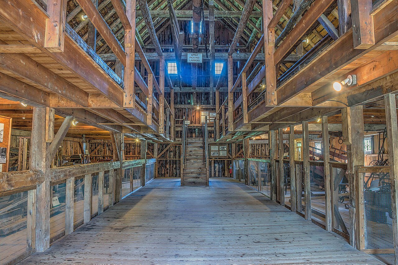 Inside a timber-framed barn at the homestead, with its aisle running to a bright window.