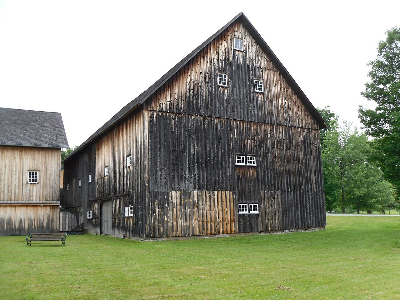 A weathered barn with a steep roof on the lawn at the state historic site.