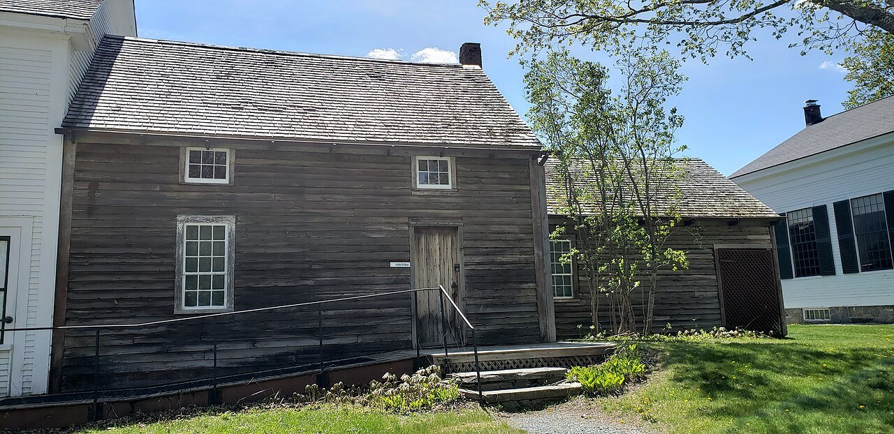 A weathered wooden house with a stone step, identified as the Coolidge birthplace, in the village.