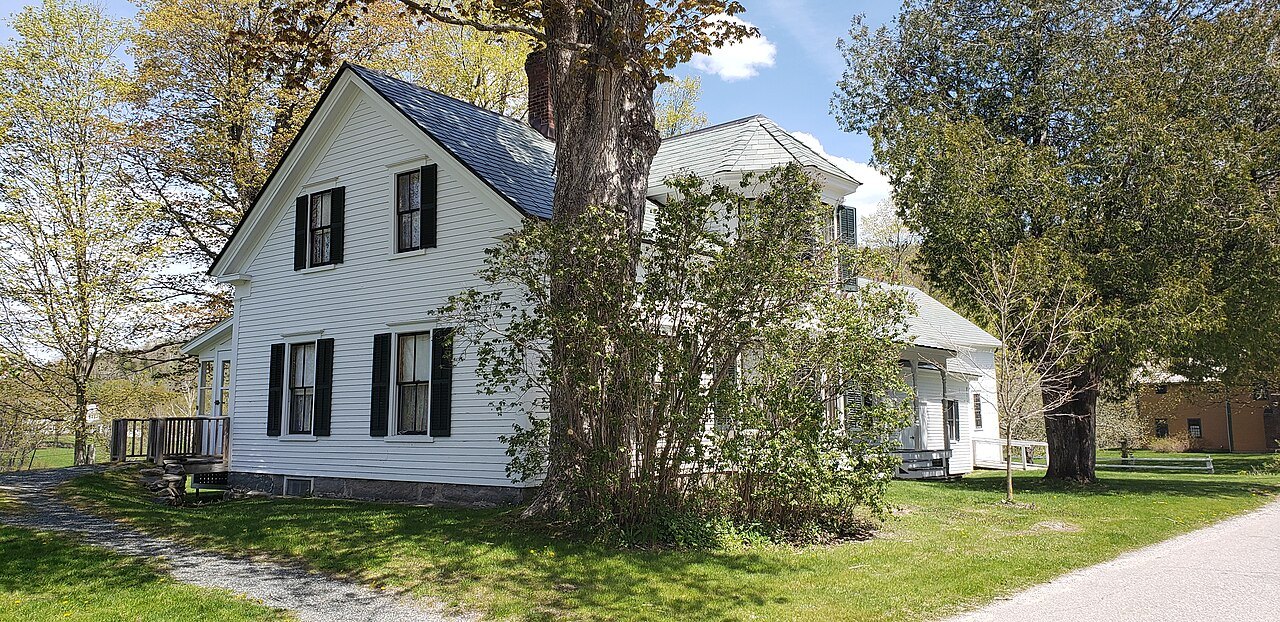 The Coolidge homestead, a white clapboard farmhouse under a large tree.