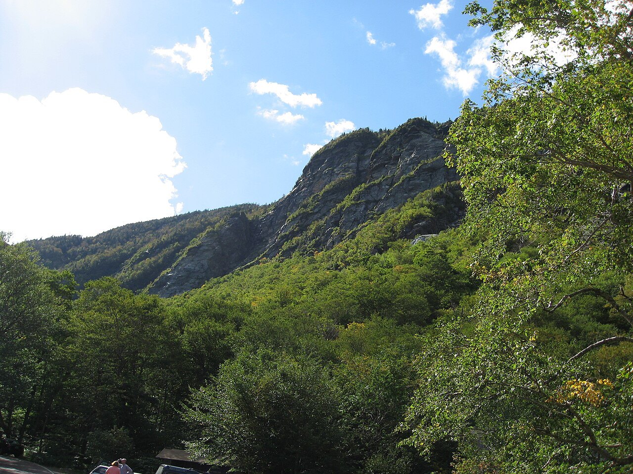 The cliff of Smugglers' Notch rising above green forest in Smugglers' Notch State Park.