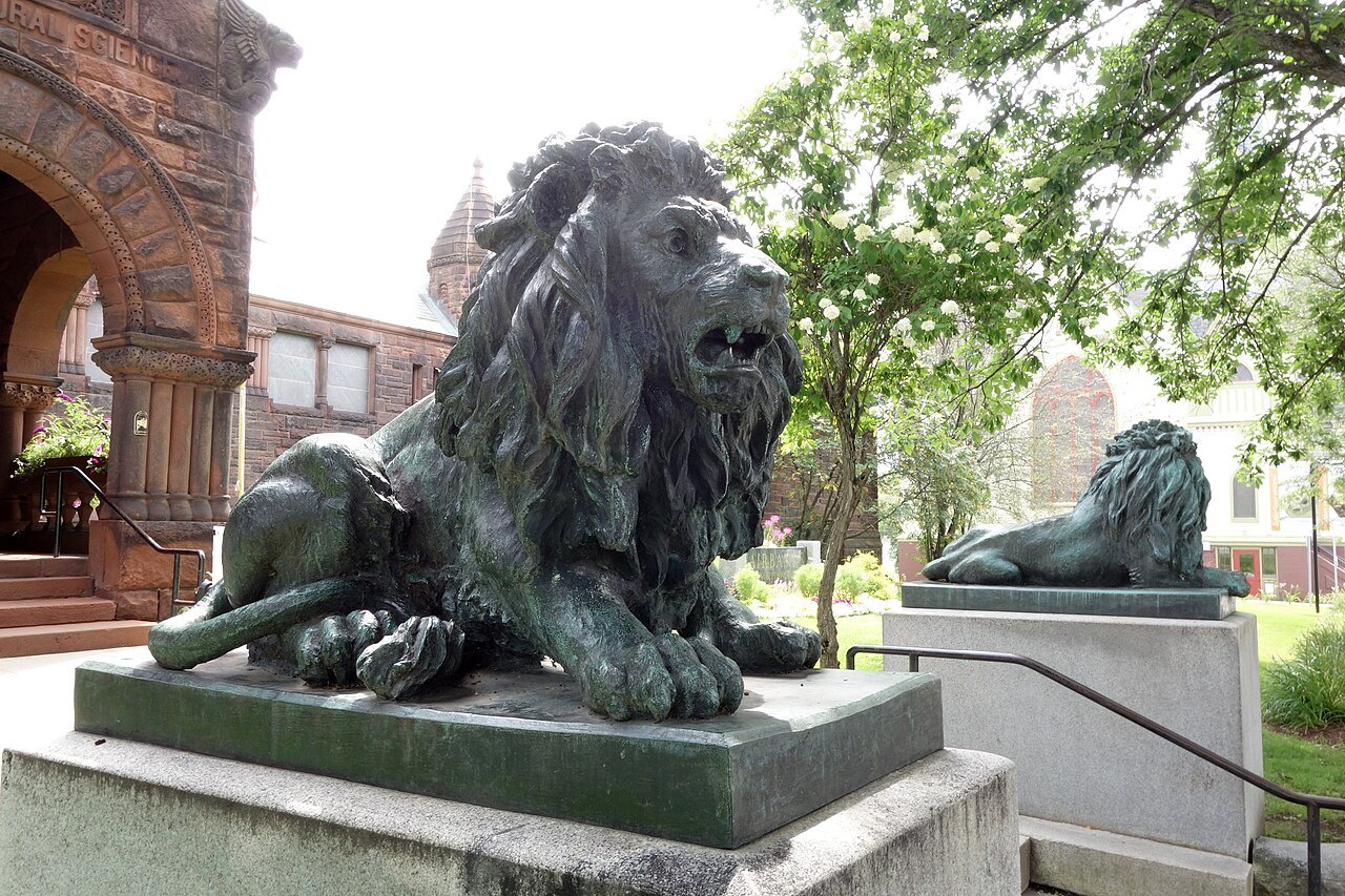 The bronze lions at the museum's entrance, with a red sandstone wall behind.