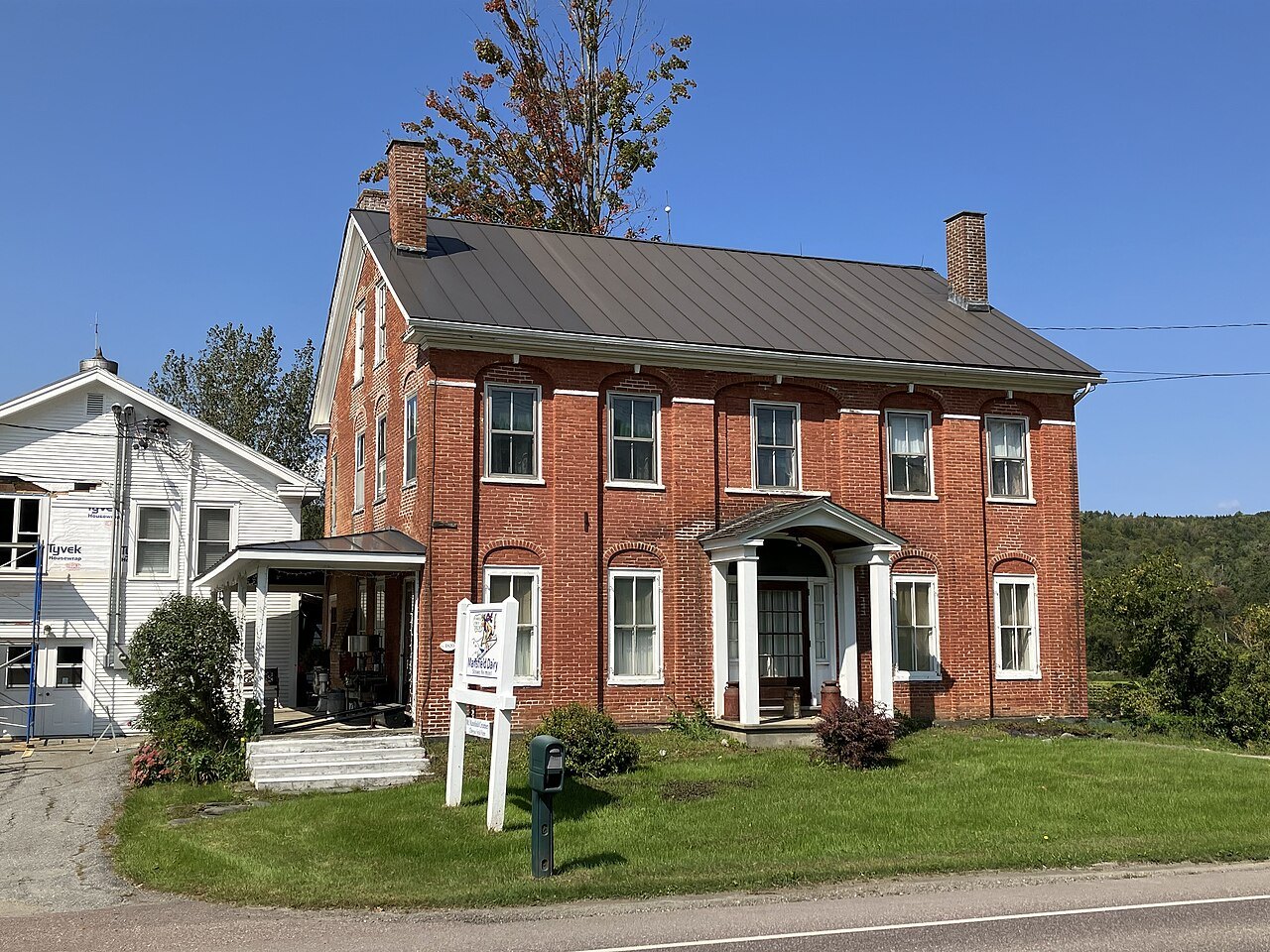 A red-brick Federal house with a pillared doorway beside a road in Stowe.